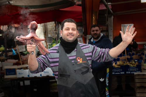 Restaurant owner dancing with an octopus to advertise his delicious food in Palermo on the Italian island of Sicily