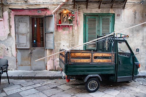 Mini-lorry Ape in front of a house with a religious wayside shrine, seen in Ballarò, Palermo, Sicily, Italy.