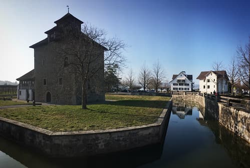 Historic stone castle with moat and traditional village houses in Pfaeffikon, Schwyz, Switzerland, March 2019