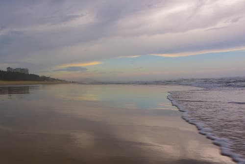 A gray sky reflected in a wet beach
