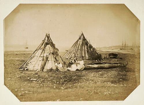 Four Mi'kmaq women sitting in front of their wigwams / Quatre femmes Mi'kmaq assises en face de leurs wigwams