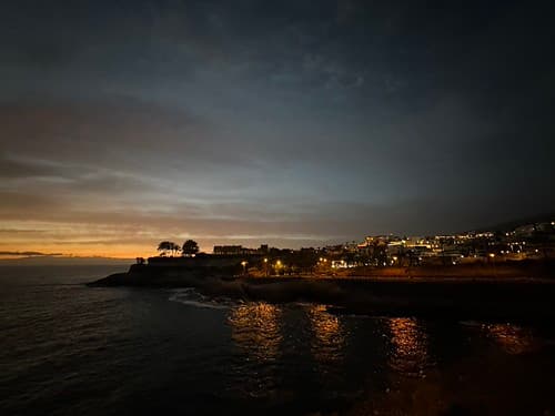 Coastal lights reflecting on the water at dusk, Playas del Duque, Adeje, Tenerife, Canary Islands, Spain, March 2023