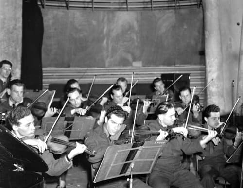 The string section of the Canadian Army orchestra during a broadcast of The Army Show, London, England / La section des cordes de l’Armée canadienne pendant l’enregistrement de la revue musicale The Army Show, Londres (Angleterre)